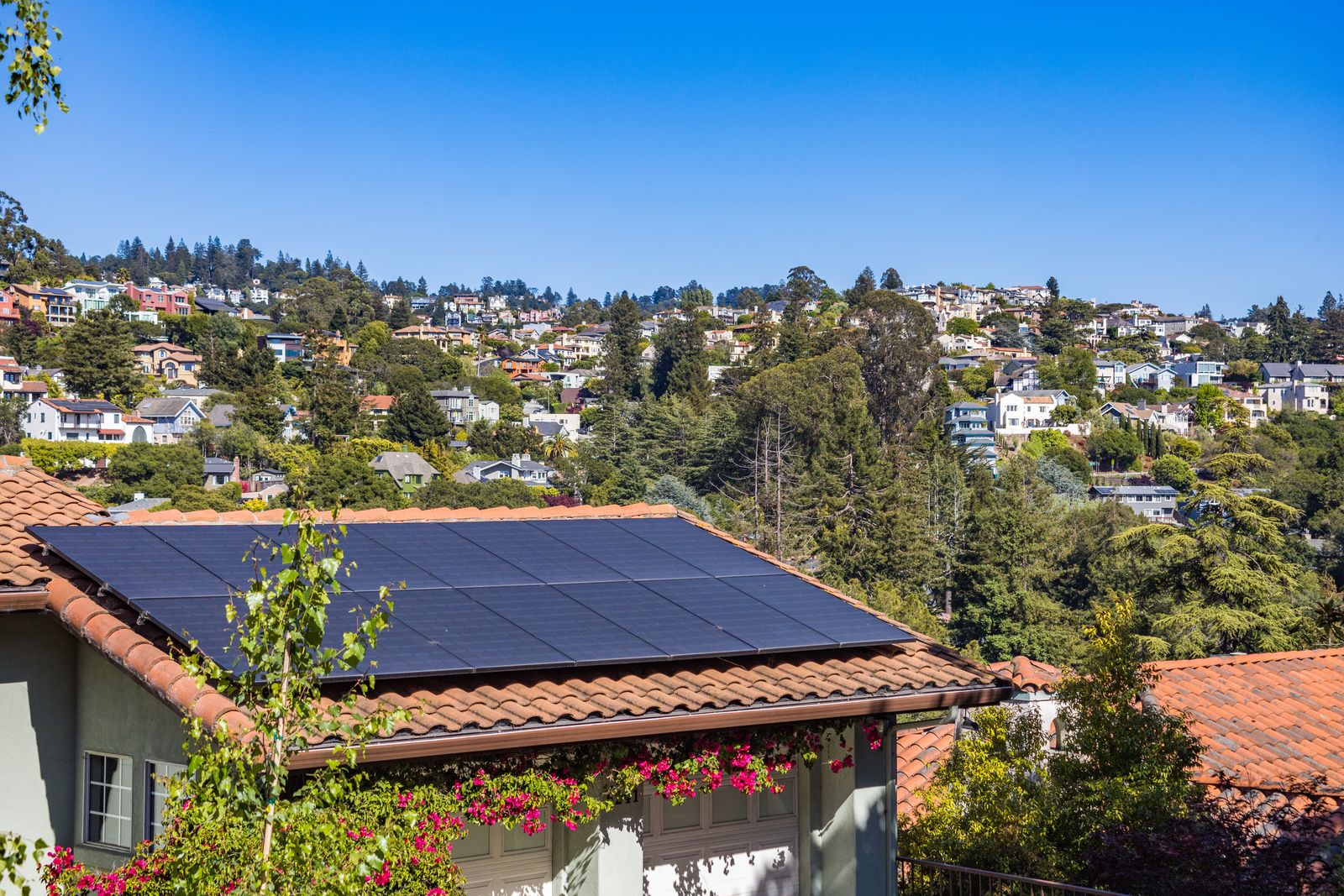 Solar panels on the tiled roof of a family home surrounded by trees